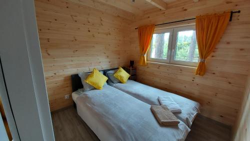 Cama en habitación de madera con ventana en Farwne checze en Wdzydze Kiszewskie