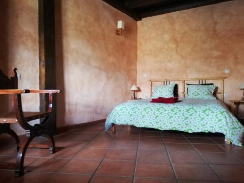 a bedroom with a bed with a green bedspread at LA FRAGUA - CASA RURAL EN VILLANUEVA DE GOMEZ (AVILA) in Villanueva de Gómez