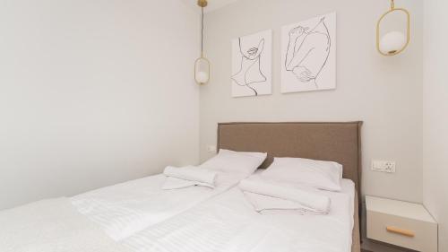a bedroom with a bed with white sheets and drawings on the wall at Apartament Baltic Garden&Sztutowo in Sztutowo