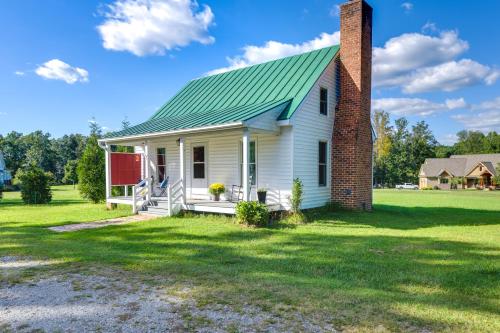 a white house with a green roof and a brick chimney at Tranquil Cottage in Virginia Countryside with Pond! in Midlothian