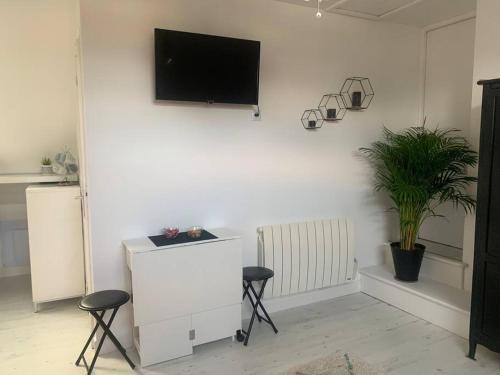 Habitación blanca con 2 taburetes y TV en la pared en Studio rénové tout confort, en Donnery