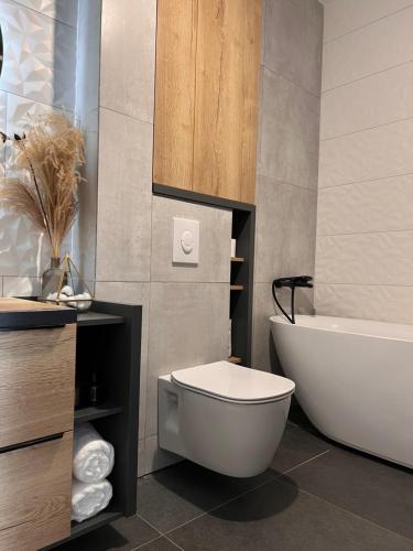 een badkamer met een bad, een toilet en een wastafel bij Bright & Modern 3 Room Apartment with All Amenities and Underground parking in Timişoara
