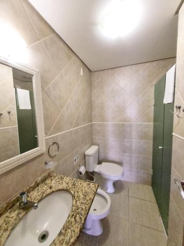 a bathroom with a sink and a toilet and a mirror at Apart Hotel Beira do Mar in Florianópolis