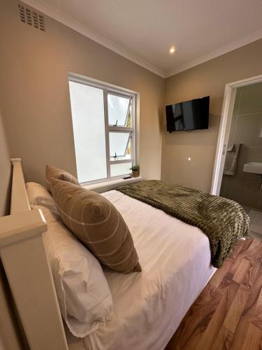 a bedroom with a bed with pillows and a window at Camellia Cottage: Courtyard Room in Cape Town