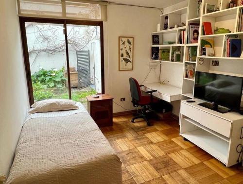 a bedroom with a bed and a desk and a television at Casa Oasis en Providencia in Santiago