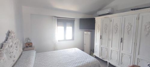 a white bedroom with a bed and a window at Mirador de Garciez in Torre del Campo
