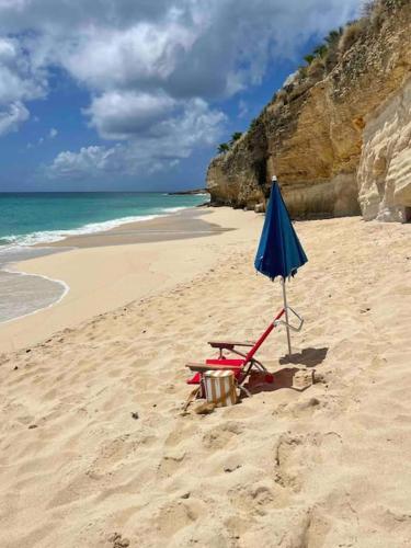 a beach with a chair and an umbrella on the sand at Beachfront luxury 2br condo in Lowlands