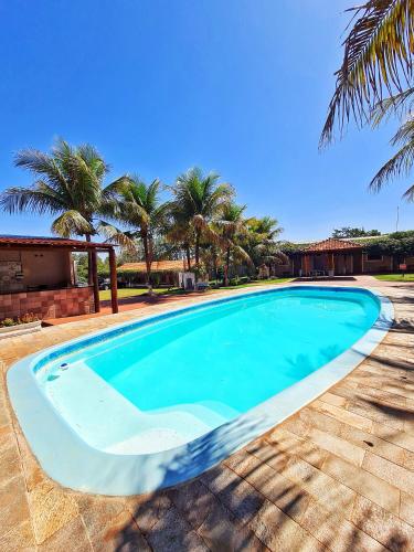 a large blue swimming pool with palm trees in the background at POUSADA POR DO SOL in Olímpia