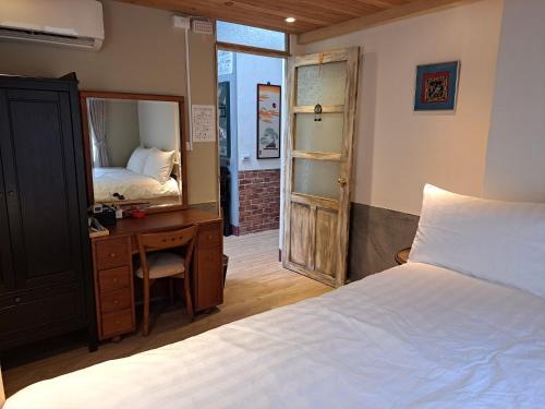 a bedroom with a bed and a desk and a mirror at 古都101民宿 適合2至7人包棟 in Tainan