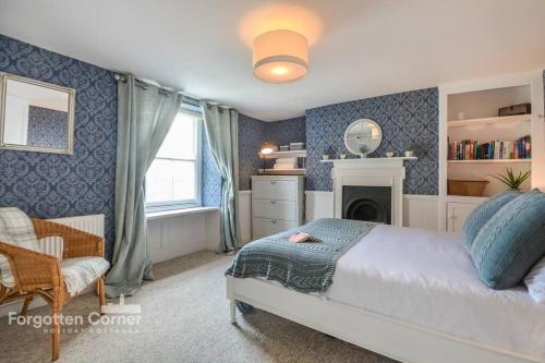 a bedroom with a bed and a chair and a fireplace at Sunnyside, Kingsand in Kingsand