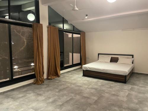 Glass Luxe Villa في مومباي: غرفة نوم بسرير ونوافذ كبيرة