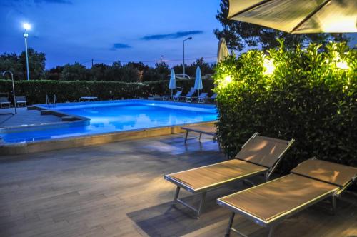 a swimming pool with two chairs and an umbrella at Residence Sunbeam in Leporano Marina