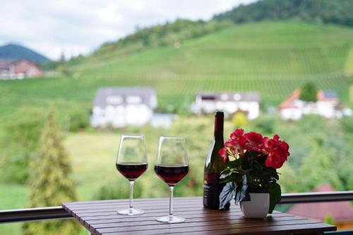 two glasses of wine and a bottle and flowers on a table at Hotel Faxe Schwarzwälder Hof in Kappelrodeck
