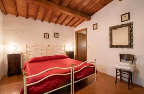 een slaapkamer met een rood bed en een stoel bij Tenuta La Cella - Grande Appartamento in Arezzo