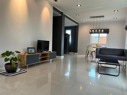 a living room with a couch and a tv at Happy home บ้านกว้าง ได้ทั้งหลัง ไวไฟฟรี1000Mbps ใกล้สนามบินสุวรรณภูมิ in Min Buri
