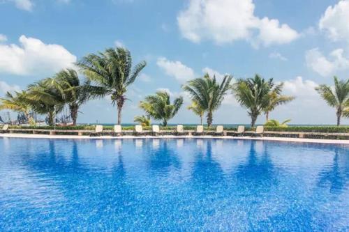 una gran piscina con palmeras en el fondo en REEF Beachfront 3BDR apartment by CASA PARAISO, en Cancún
