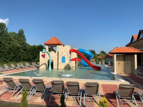 a pool with chairs and a water slide at Termál Hotel Vesta in Tápiószecső