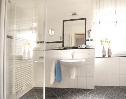 a white bathroom with a sink and a mirror at Hotel & Ferienappartements Edelweiss in Willingen