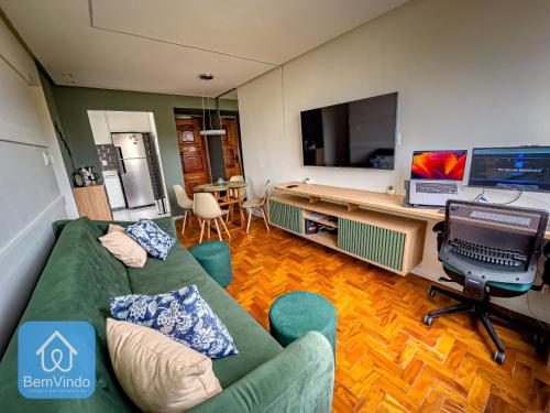 a living room with a green couch and a flat screen tv at Apartamento Completo e Aconchegante no Centro in Salvador