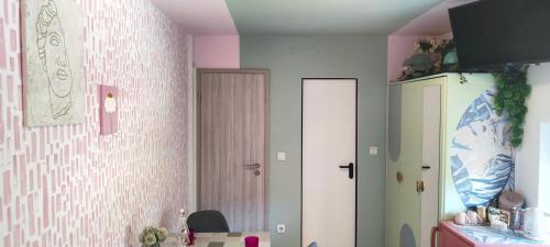 Apartments & rooms Saša في بوتْشيترتيك: مطبخ بجدران وردية وبيضاء وثلاجة