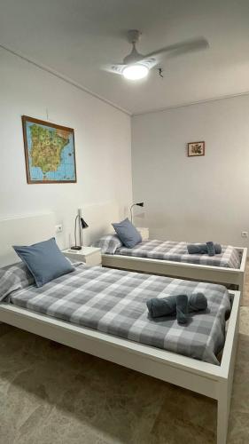 2 Betten in einem weißen Zimmer mit blauen Kissen in der Unterkunft Preciosa a 2 min Renfe in Gandía