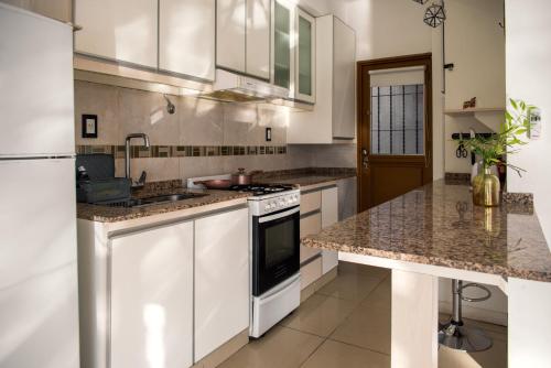 kuchnia z białymi szafkami i granitowymi blatami w obiekcie Premium Gold Mendoza w mieście Mendoza