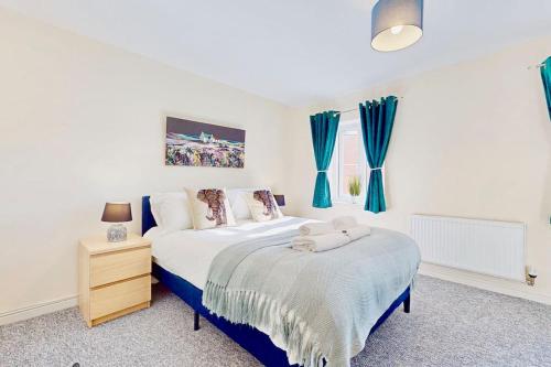 Super Quiet 4 Bed Family House in Gravesend في Kent: غرفة نوم بسرير كبير مع ستائر زرقاء