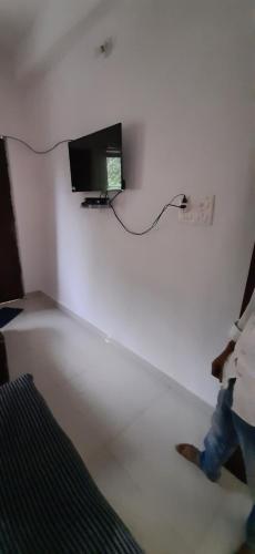 una persona caminando en una habitación con TV en la pared en Kalawati Niwas en Bodh Gaya