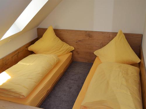 2 Betten in einem Zimmer mit gelber Bettwäsche und Kissen in der Unterkunft Libelle in Colmberg