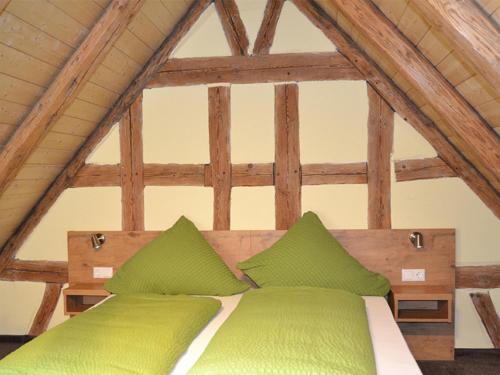 a bed with green pillows in a attic at Kleebock in Colmberg