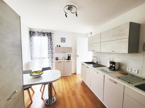 une cuisine avec des armoires blanches et une table à l'intérieur dans l'établissement T3 rénové, 4 couchages, entre Aix et Marseille, à Marseille