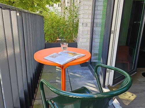 an orange table and two green chairs on a patio at STAYERY Bremen in Bremen