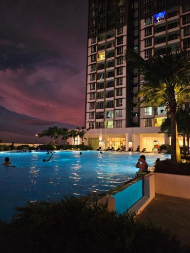 a swimming pool at night with a tall building at METROPOL SERVICED APARTMENT at Bukit Mertajam, Pulau Pinang in Bukit Mertajam