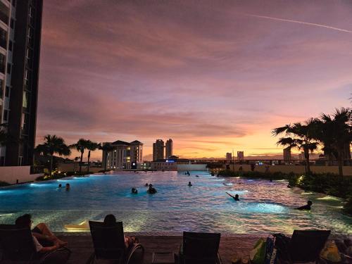 a group of people swimming in a swimming pool at sunset at METROPOL SERVICED APARTMENT at Bukit Mertajam, Pulau Pinang in Bukit Mertajam