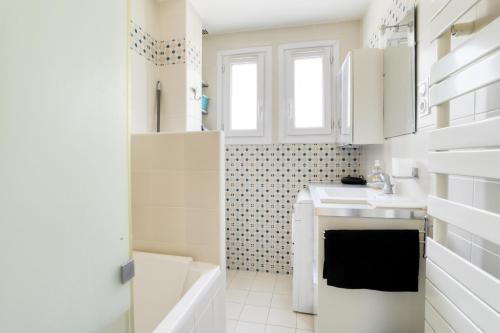 La salle de bains blanche est pourvue d'un lavabo et d'une baignoire. dans l'établissement Time of Travel - à 20min des Champs-Élysées, à Rueil-Malmaison