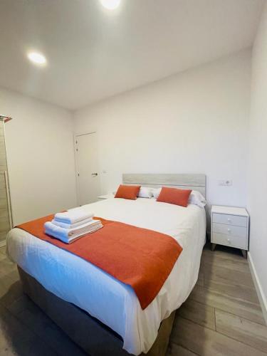 1 dormitorio con 1 cama grande con sábanas de color naranja y blanco en Apartamentos Rurales La Plaza 2, en Duruelo de la Sierra