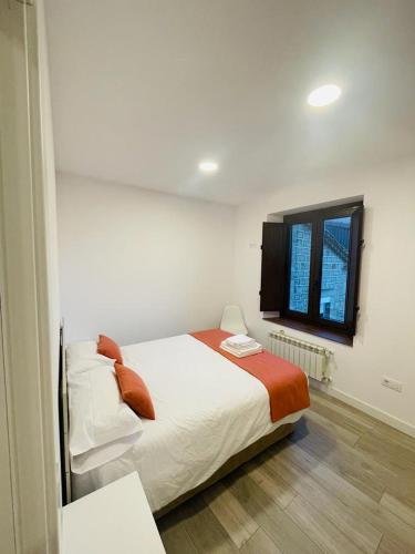 a white bedroom with a bed and a window at Apartamentos Rurales La Plaza 2 in Duruelo de la Sierra