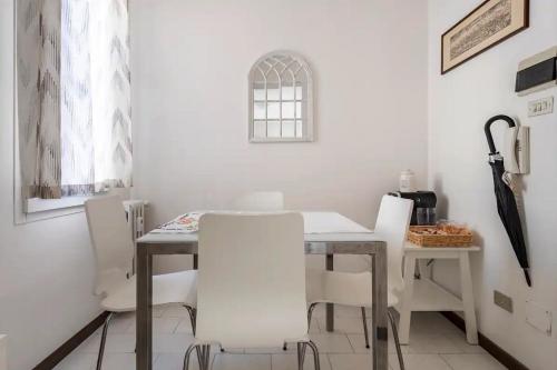 a dining room with a table and white chairs at Appartamento Pescherie - Top location in Bologna