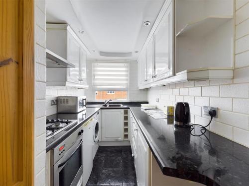 a kitchen with white appliances and black counter tops at Parsonage Leys in Harlow