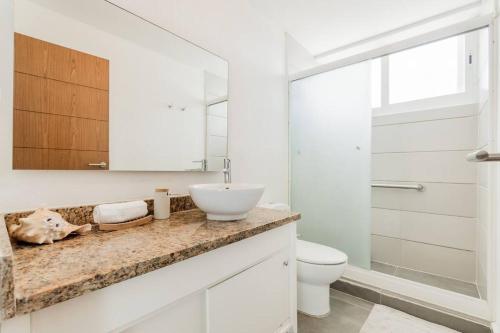 a white bathroom with a sink and a toilet at REEF Beachfront 3BDR apartment by CASA PARAISO in Cancún