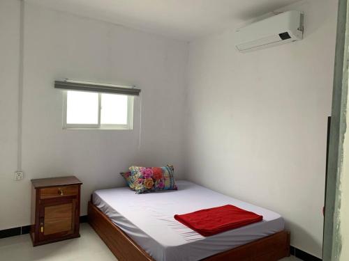 a small white room with a bed and a window at Home Daun Kam 1 in Kampot