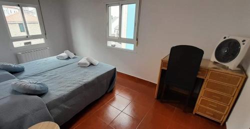 a bedroom with a bed and a desk and two windows at La Huella del Peregrino in Palas de Rei