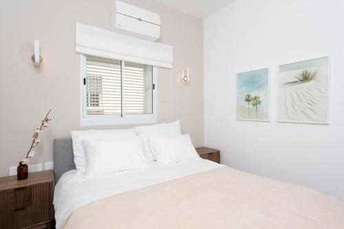 a white bedroom with a bed and a window at HOMEZ- Carmel Market in Tel Aviv