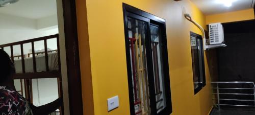 a room with a yellow wall and a mirror at Hostel Rococo Pelton Palolem Beach in Canacona