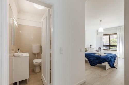 a white bathroom with a toilet and a sink at Massamá 26 / free park on premises/ smart TV in Queluz
