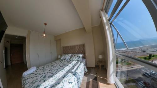 een slaapkamer met een bed en een groot raam bij Ocean Apartments in Lima