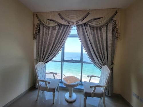 a room with a table and chairs and a large window at Beachfront Holiday Homes in Ajman 