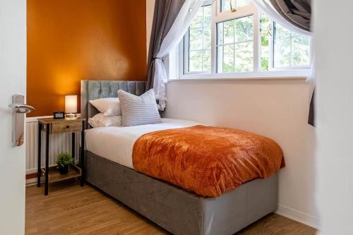 um quarto com uma cama com um cobertor laranja e uma janela em 2 Bed House near the London Museum em Londres