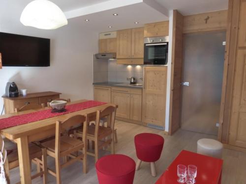 une cuisine avec une table en bois et des chaises rouges dans l'établissement Appartement rénové 2 pièces à Méribel, vue montagne - FR-1-411-517, à Les Allues