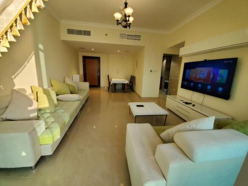 a living room with white couches and a flat screen tv at Beachfront Holiday Homes in Ajman 
